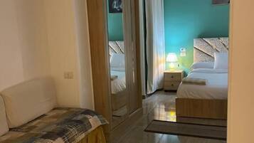 Una habitación con una cama, un sofá, una mesita redonda y un espejo.