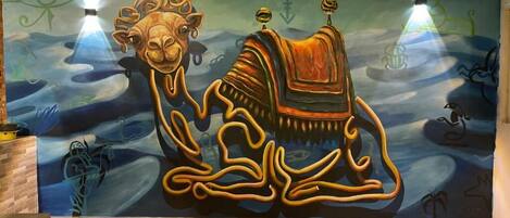 A mural with a camel and abstract designs on a wall.