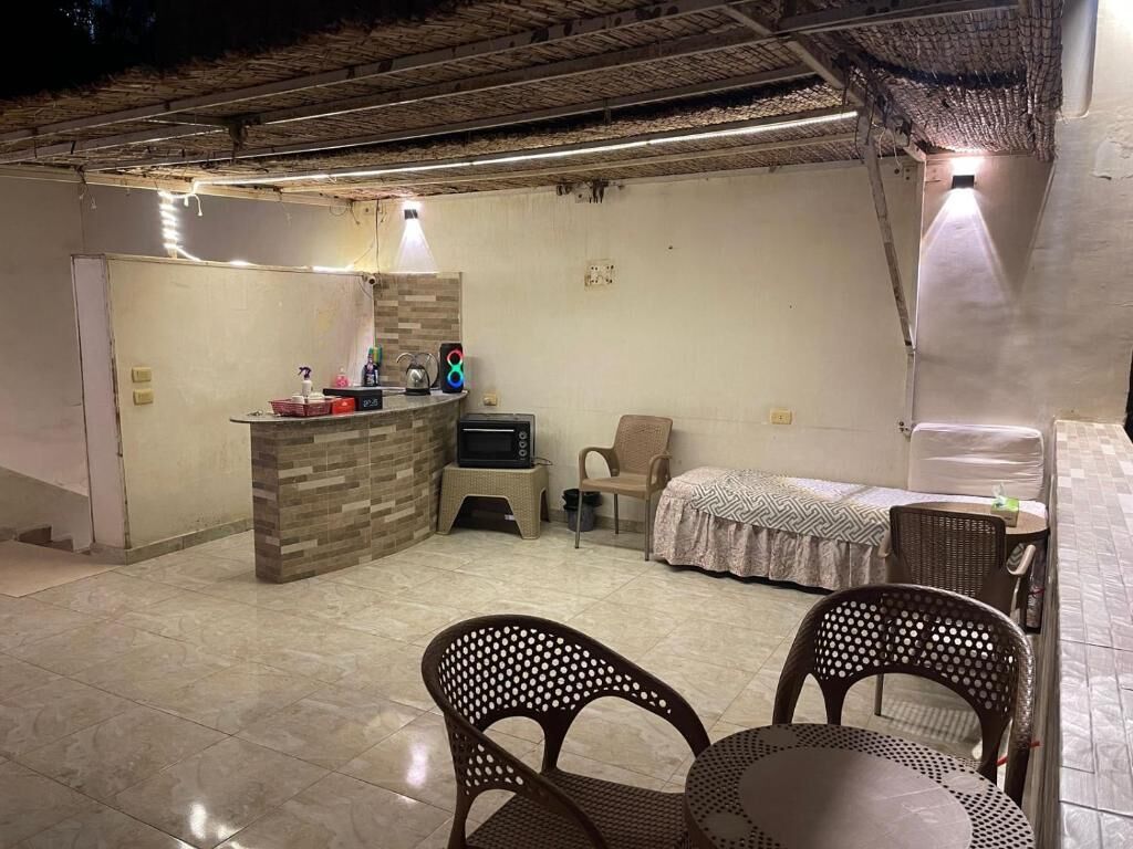 Habitació amb petita cuina, un llit, zona d'estar amb cadires i una taula.