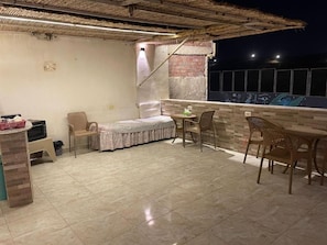 A rooftop terrace with a bed, chairs, a table, and a brick wall. - Farida Pyramids Boutique Hotel (Giza)
