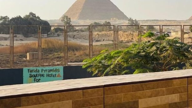 A view of the Great Pyramid of Giza from a hotel balcony with a sign for the Tarida Pyramids Boutique Hotel. - Farida Pyramids Boutique Hotel (Giza)