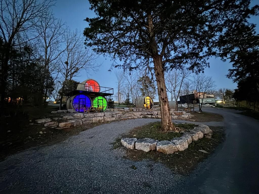 A paved pathway with a stone border, a tree, and illuminated circular structures.