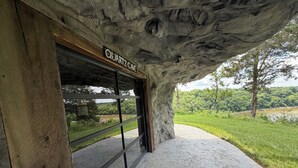 A building entrance with a sign reading 'QUARTZ CAVE,' a stone facade, and a view of a green landscape.
