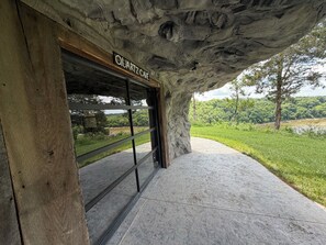 A building entrance with a sign reading 'QUARTZ CAVE,' a stone facade, and a view of a green landscape.