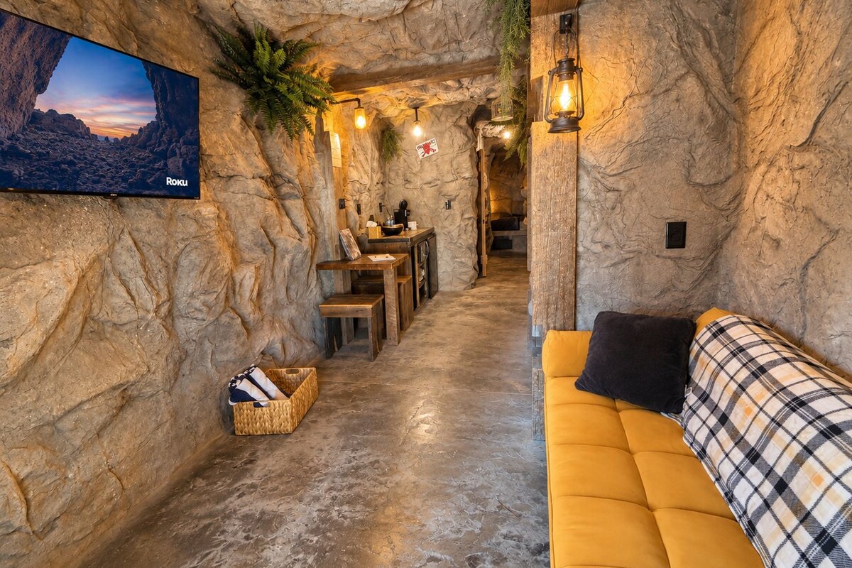 Un intérieur chaleureux avec un mur en pierre, un téléviseur à écran plat, une table en bois et un canapé jaune.