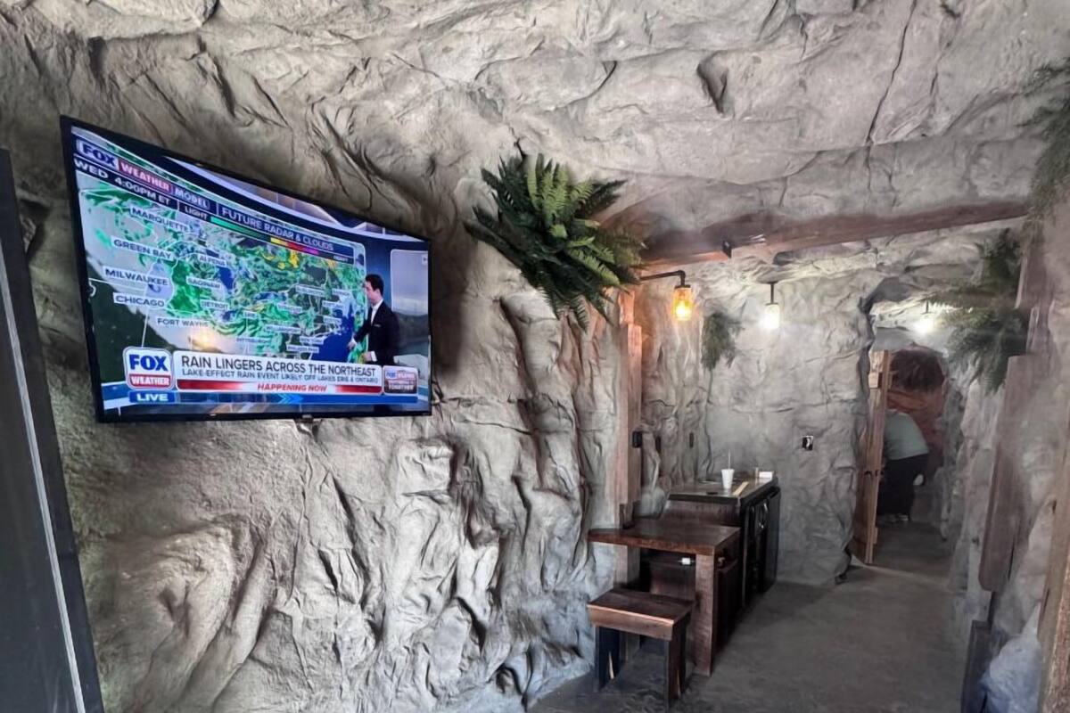 A cave-like interior with a television displaying a weather forecast.