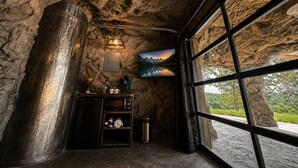 A room with a rugged stone wall, a built-in microwave, a small shelf with a coffee machine, and a large window with a mountain view. - LockRidge Park (Lancaster)