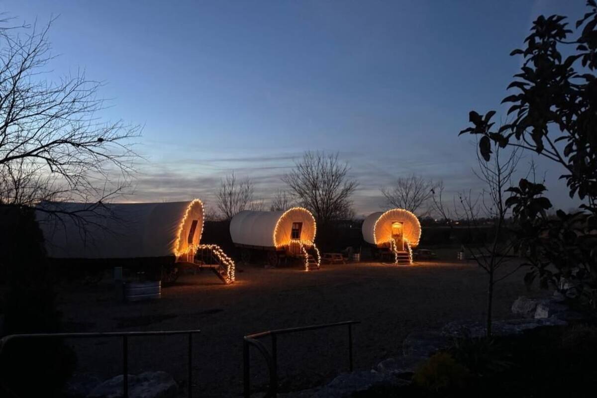 Three large, cylindrical structures with lights, possibly tents or temporary accommodations, in a rural setting.