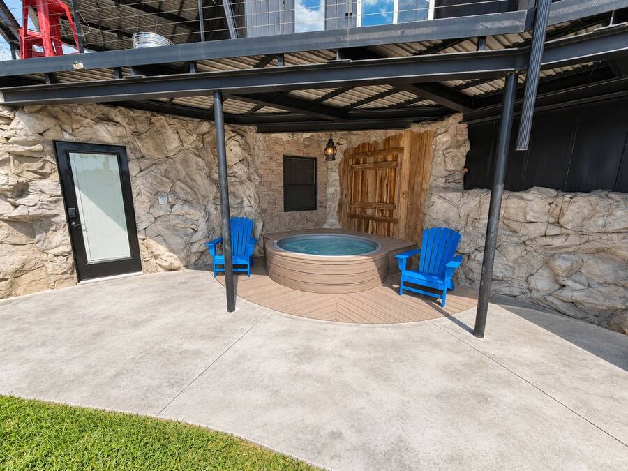 En stenvæg, et spabad og to blå stole.