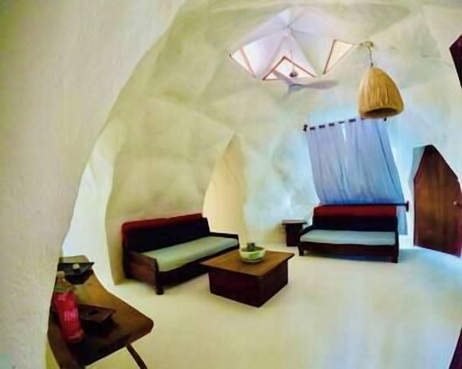 A cozy, semi-open room with a sofa, a small table, and a hanging light fixture.
