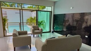 Ein modernes Wohnzimmer mit zwei Sofas, einer Glastür, die auf einen Balkon führt, und einem großen abstrakten Gemälde an der Wand.