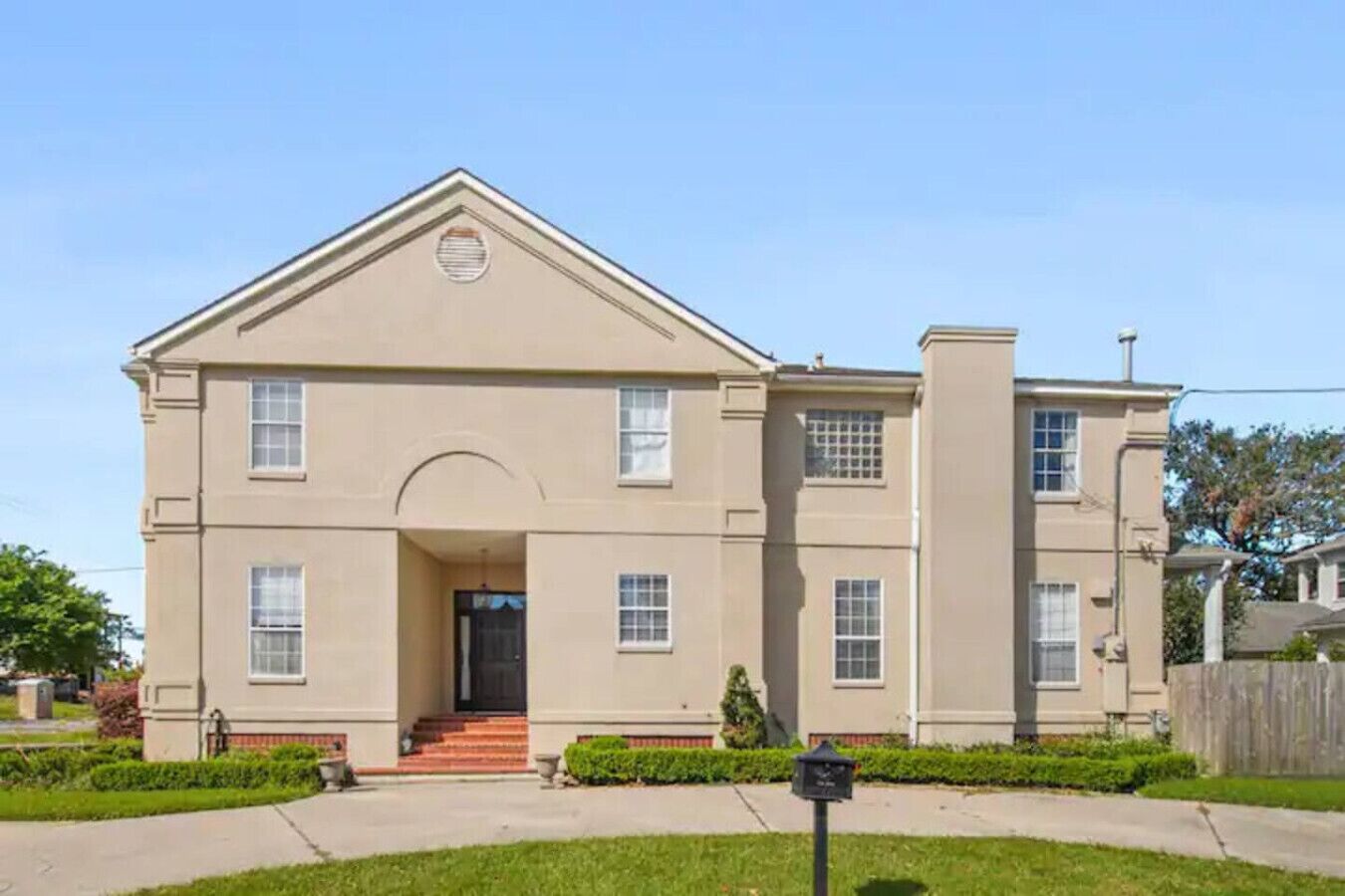 A two-story house with a symmetrical facade, a central entrance with steps, and a small porch area.