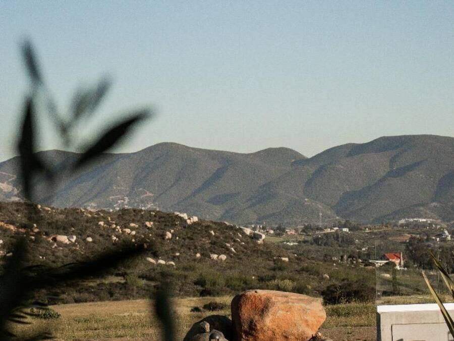 A pool area with a large rock, a mountain backdrop, and a clear sky.