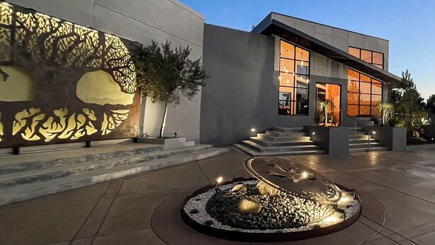 A modern building with a landscaped courtyard featuring a circular stone feature and a decorative wall with tree patterns. - VILLA SIMUL HOTEL BOUTIQUE VALLE DE GPE (Valle de Guadalupe)