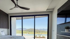 A modern bedroom with a bed, a ceiling fan, and a large sliding glass door leading to a pool area. - VILLA SIMUL HOTEL BOUTIQUE VALLE DE GPE (Valle de Guadalupe)