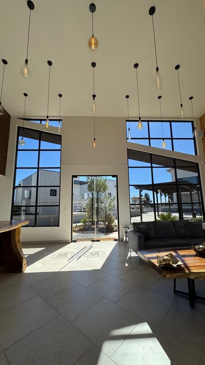 A spacious interior with large windows, a seating area, and hanging pendant lights.