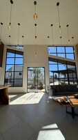 Un interior amplio con ventanas grandes, un área de estar y lámparas colgantes.