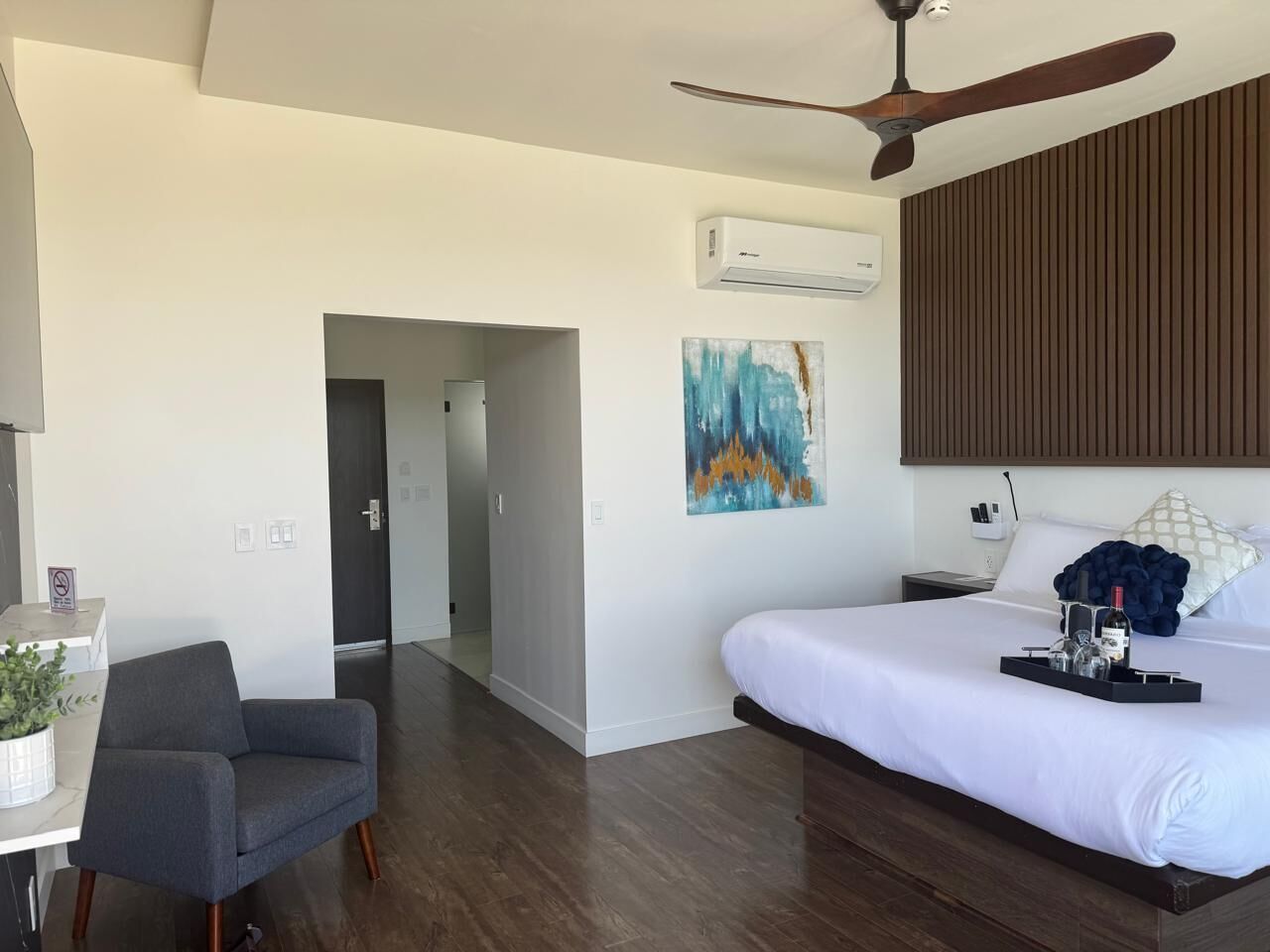 Une chambre d’hôtel moderne équipée d’un lit, d’un bureau, d’une chaise, d’un climatiseur et d’un ventilateur de plafond.