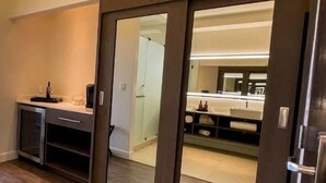 A modern kitchen with a dark countertop, a built-in oven, and a sliding door leading to a bathroom. - VILLA SIMUL HOTEL BOUTIQUE VALLE DE GPE (Valle de Guadalupe)