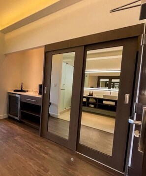 A modern kitchen with a dark countertop, a built-in oven, and a sliding door leading to a bathroom. - VILLA SIMUL HOTEL BOUTIQUE VALLE DE GPE (Valle de Guadalupe)
