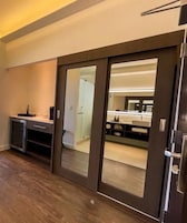 Una cocina moderna con encimera oscura, horno empotrado y puerta corredera que da a un baño.