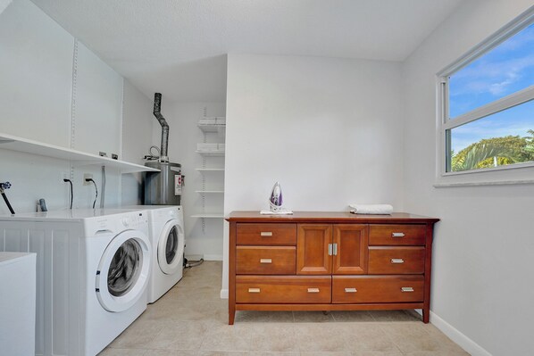 A laundry room with a washing machine, dryer, and wooden cabinet with drawers. - DREAM BEACH HOUSE With HEATED POOL (Hollywood)