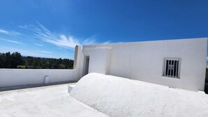 A rooftop terrace with a white building, a small window with decorative bars, and a clear blue sky. - Independent villa floor, next to the sea! ideal for families (Hammamet)