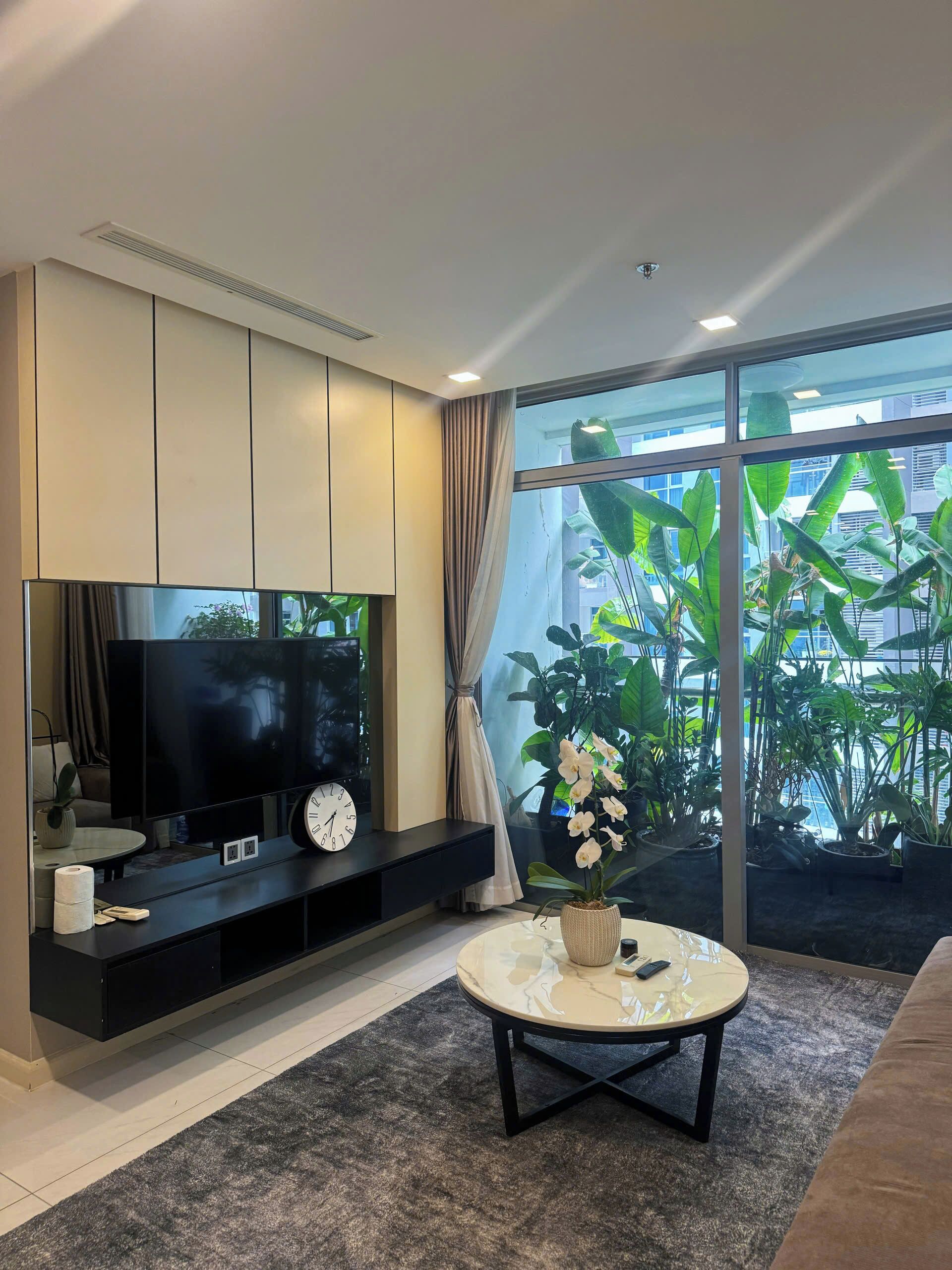 Uma sala de estar moderna com uma televisão de tela plana, um relógio e uma mesa de centro.