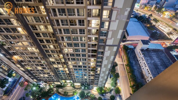 Un edificio alto con varios pisos, una piscina en la azotea con fuentes de agua y zonas verdes circundantes.