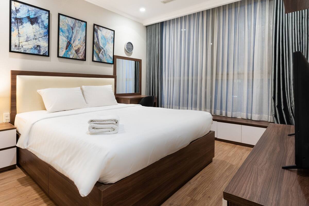 Ein Hotelzimmer mit einem großen Bett, einem Schreibtisch, einem Fernseher und Bildern an der Wand.