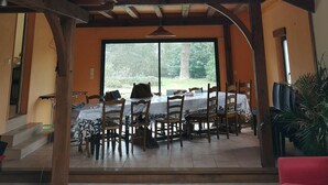 A dining area with a high ceiling and skylight, wooden beams, and a view of the outdoors.