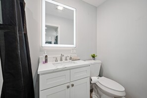 Een badkamer met een wit wastafel, een spiegel, een toilet en een douchegordijn.