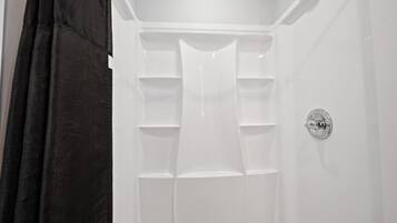 Ducha blanca con grifo Delta y varios estantes para almacenamiento.