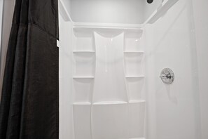 Eine weiße Dusche mit einem Delta-Wasserhahn und mehreren Ablageflächen.