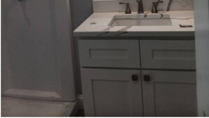 A bathroom with a white sink, a mirror, and a shower.