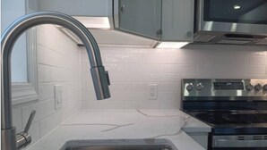 A modern kitchen with a stainless steel sink, a built-in oven, and a microwave.