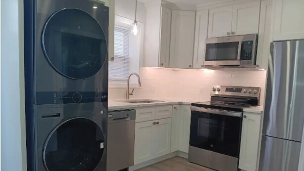 A modern kitchen with stainless steel appliances, white cabinetry, and a double oven.