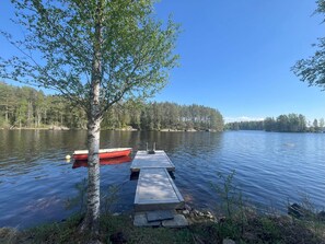 A calm lake with a dock and a red boat.