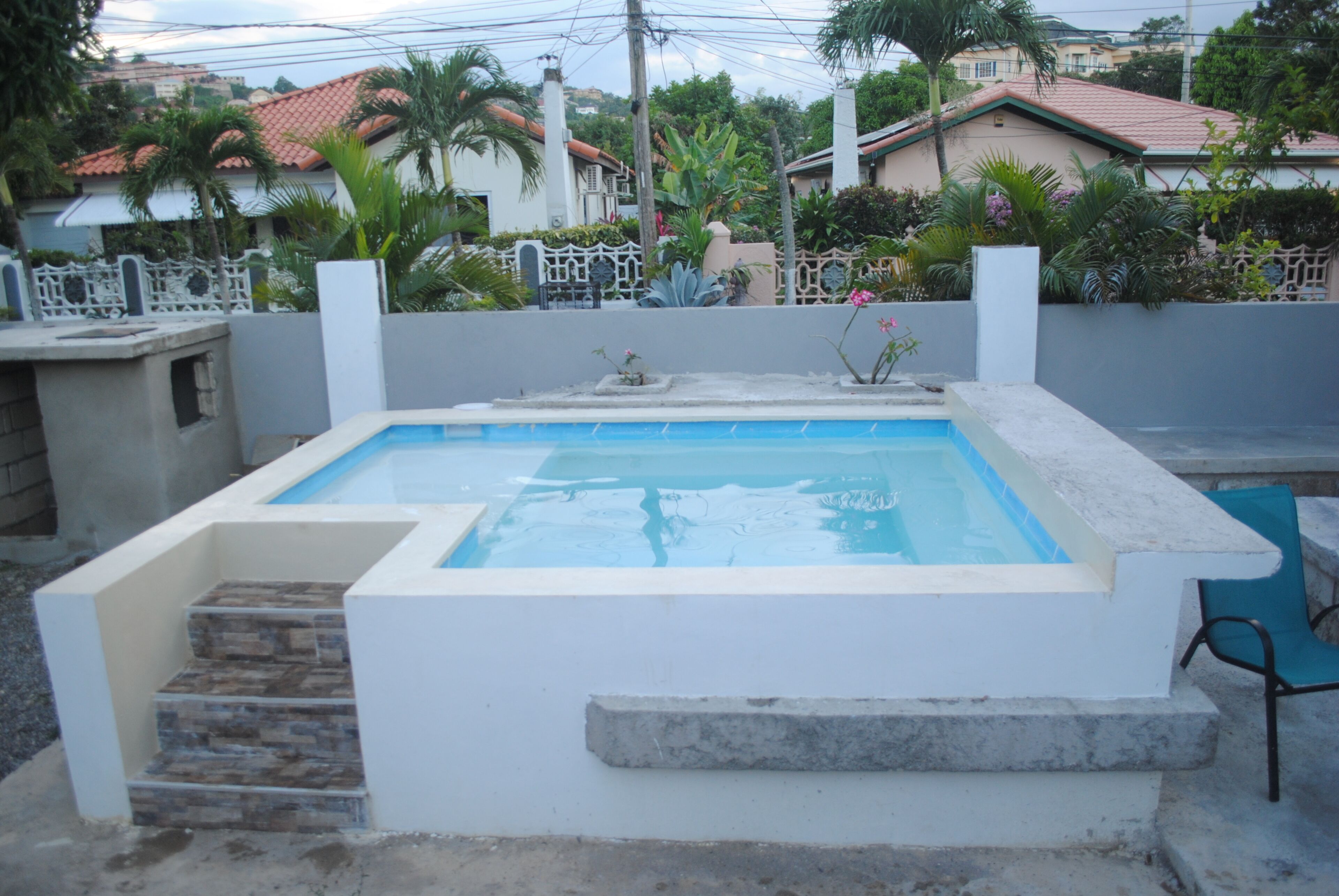 Una piscina rectangular con borde de piedra y escalones de acceso.