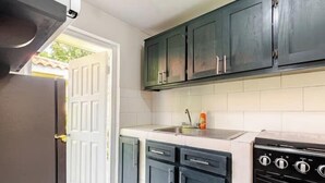 A kitchen with dark cabinets, a stove, and a sink.