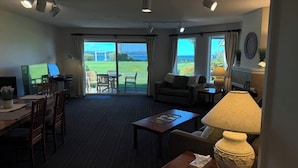 Habitación de hotel con comedor, sofá, lámpara y vistas al exterior.
