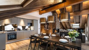 A modern kitchen with a central island, built-in appliances, and a dining area with a wooden table and chairs. - Wifi, 4th floor, view mountain, sauna, hammam, balcony, fireplace or stove, tv, 148m², Méribel (Méribel - Les Allues)