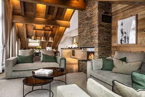 A modern living room with a stone fireplace, wooden beams, and a cozy seating area. - Wifi, 150m from ski slopes, 4th floor, view mountain, sauna, hammam, balcony, fireplace or stove, tv (Méribel - Les Allues)