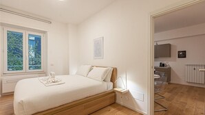 Une chambre à coucher moderne avec un lit en bois, une table de chevet, un radiateur et une vue sur l’extérieur.