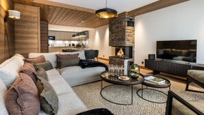 Una sala de estar moderna con una chimenea de piedra, un sofá, una mesa de centro y un televisor.