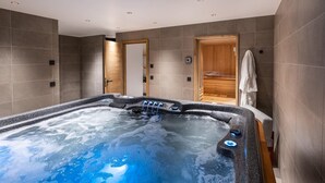 Un moderno spa con un amplio jacuzzi, puertas de madera y un perchero.