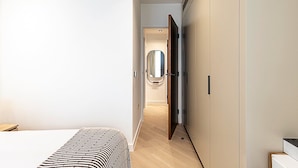 A modern bedroom with a bed, a bedside table, a wardrobe, and a mirror. - Elegant Flat in Notting Hill's Heartbeat (London)