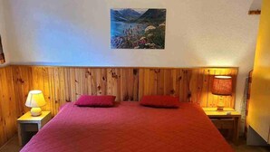 A bedroom with a large bed, wooden headboard, two bedside lamps, and a painting on the wall.