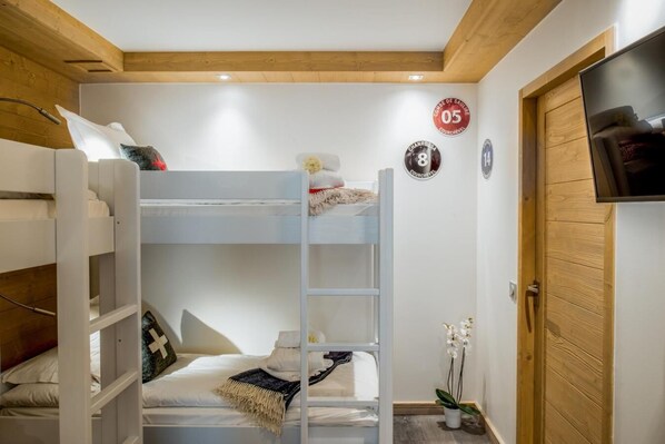 Ein Schlafzimmer mit Etagenbetten, Holzboden, einem Fernseher und einer Tür.