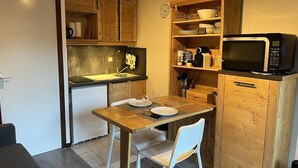 Une cuisine compacte dotée de meubles en bois, d’un four à micro-ondes et d’une table à manger avec des chaises.